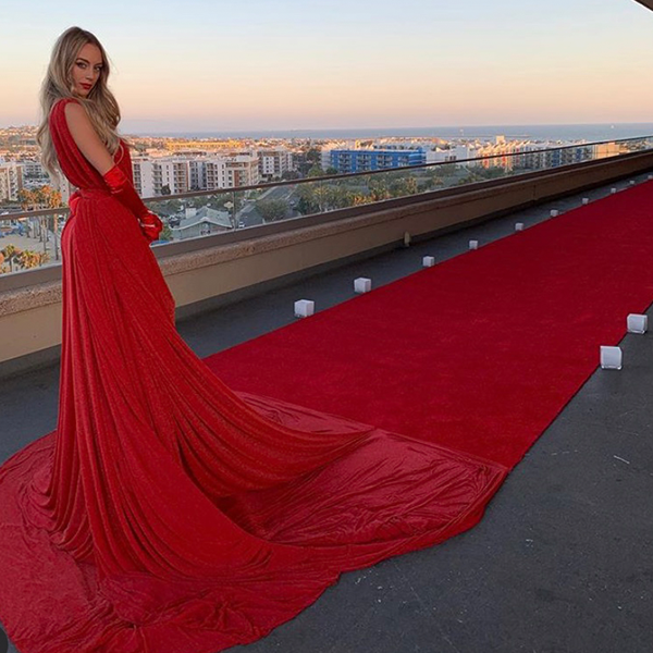 A woman in a long red dress is standing on a red carpet