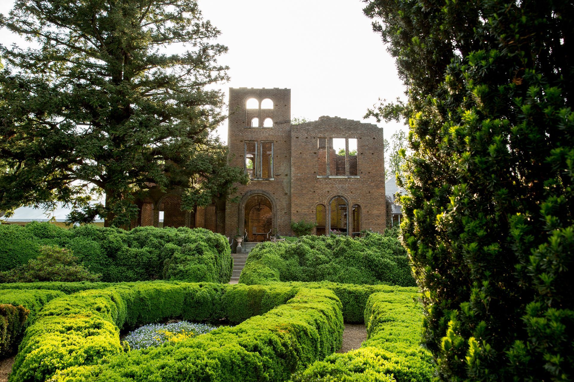 A large brick building is surrounded by bushes and trees