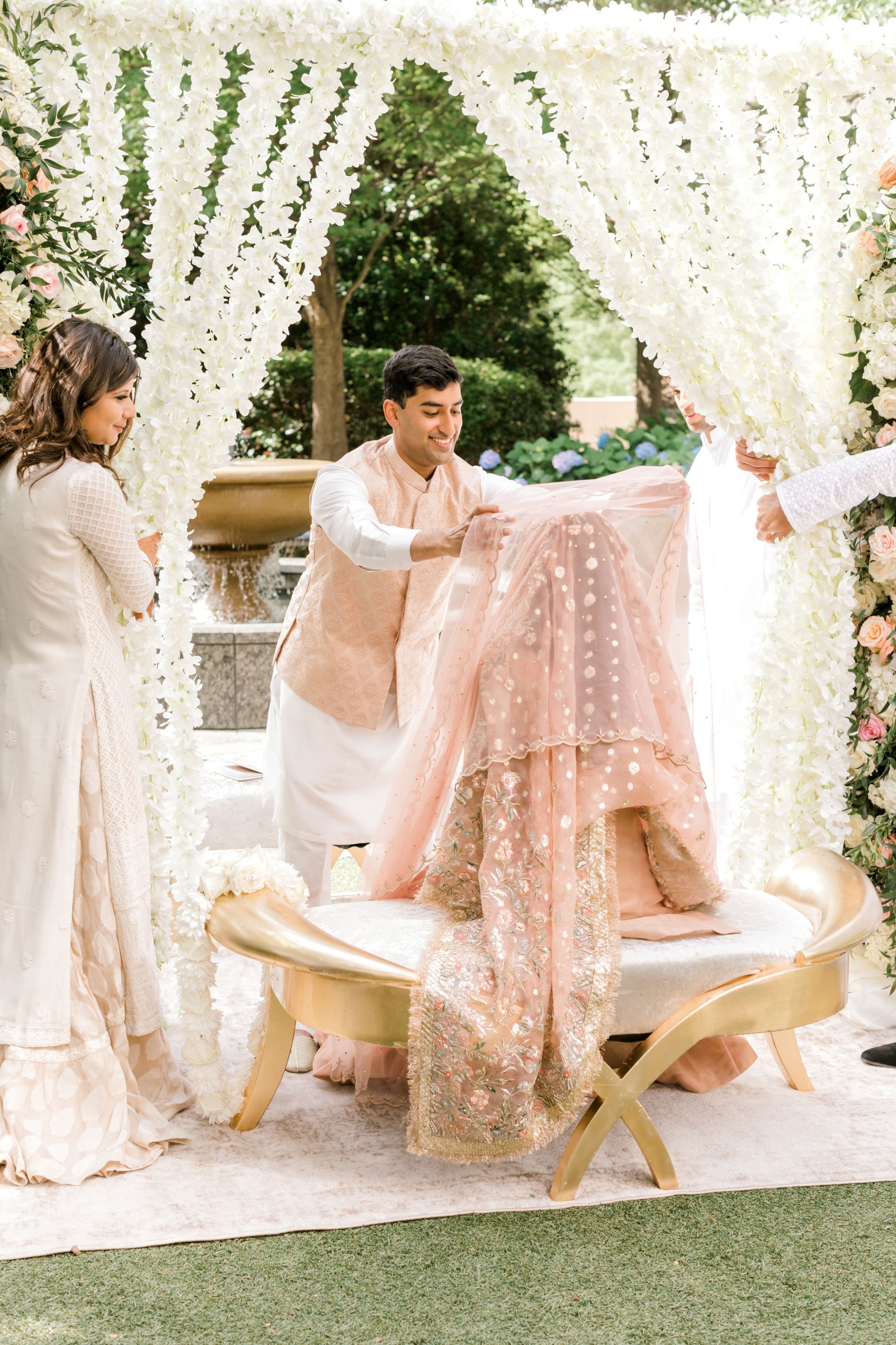 A bride and groom are getting ready for their wedding ceremony under a canopy of white flowers.