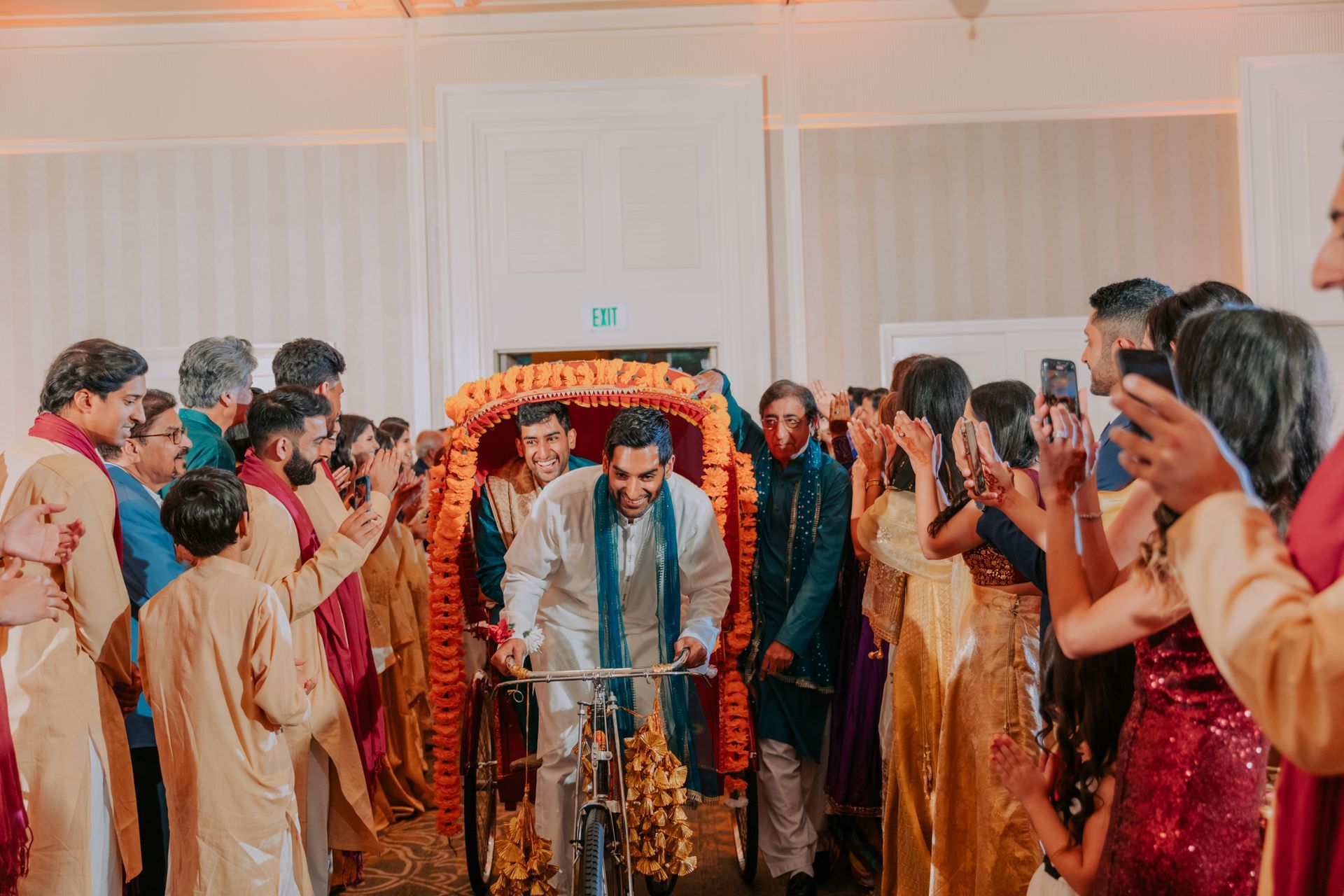 A man is riding a bicycle through a crowd of people at a wedding.