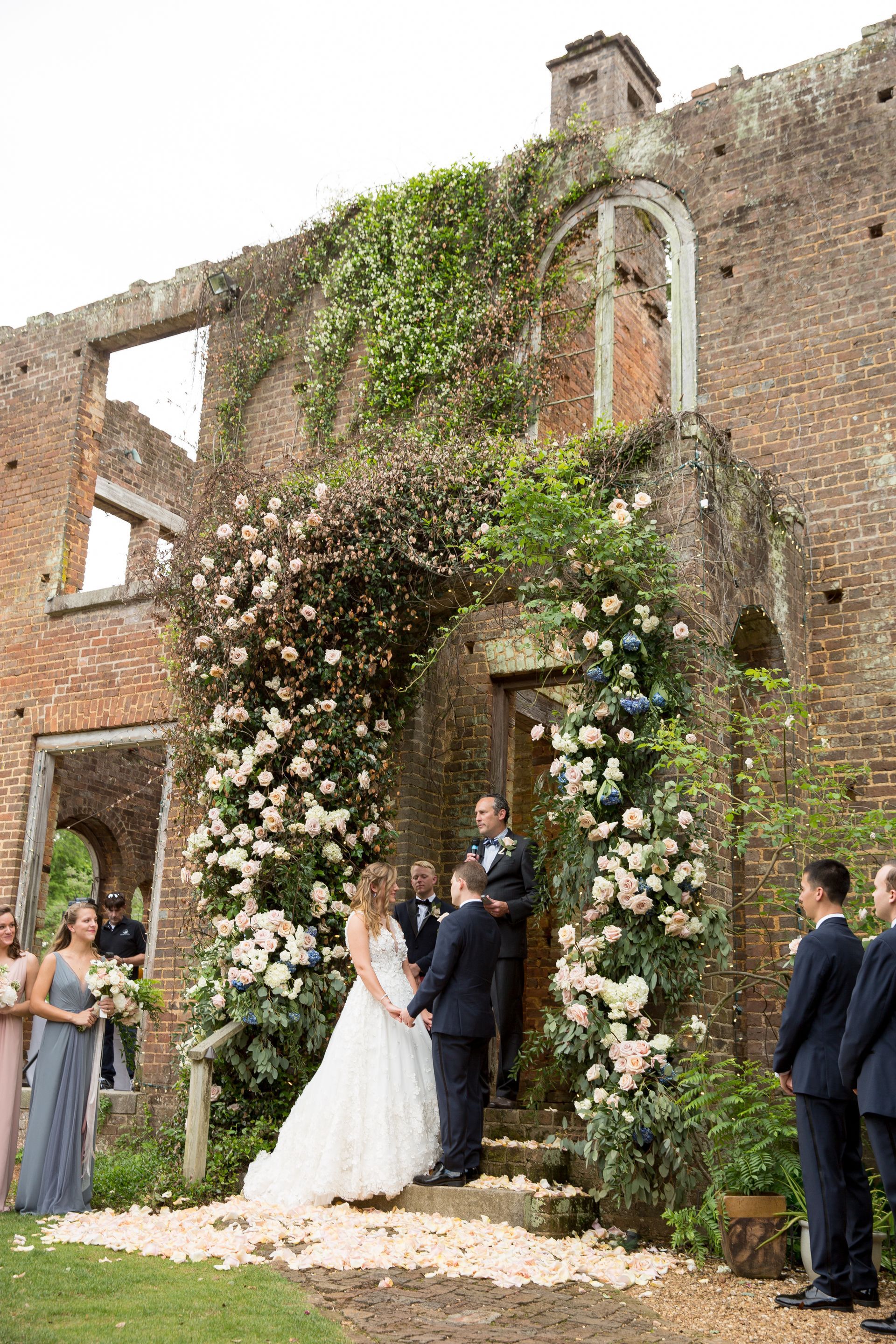 A bride and groom are getting married in front of a ruined building.