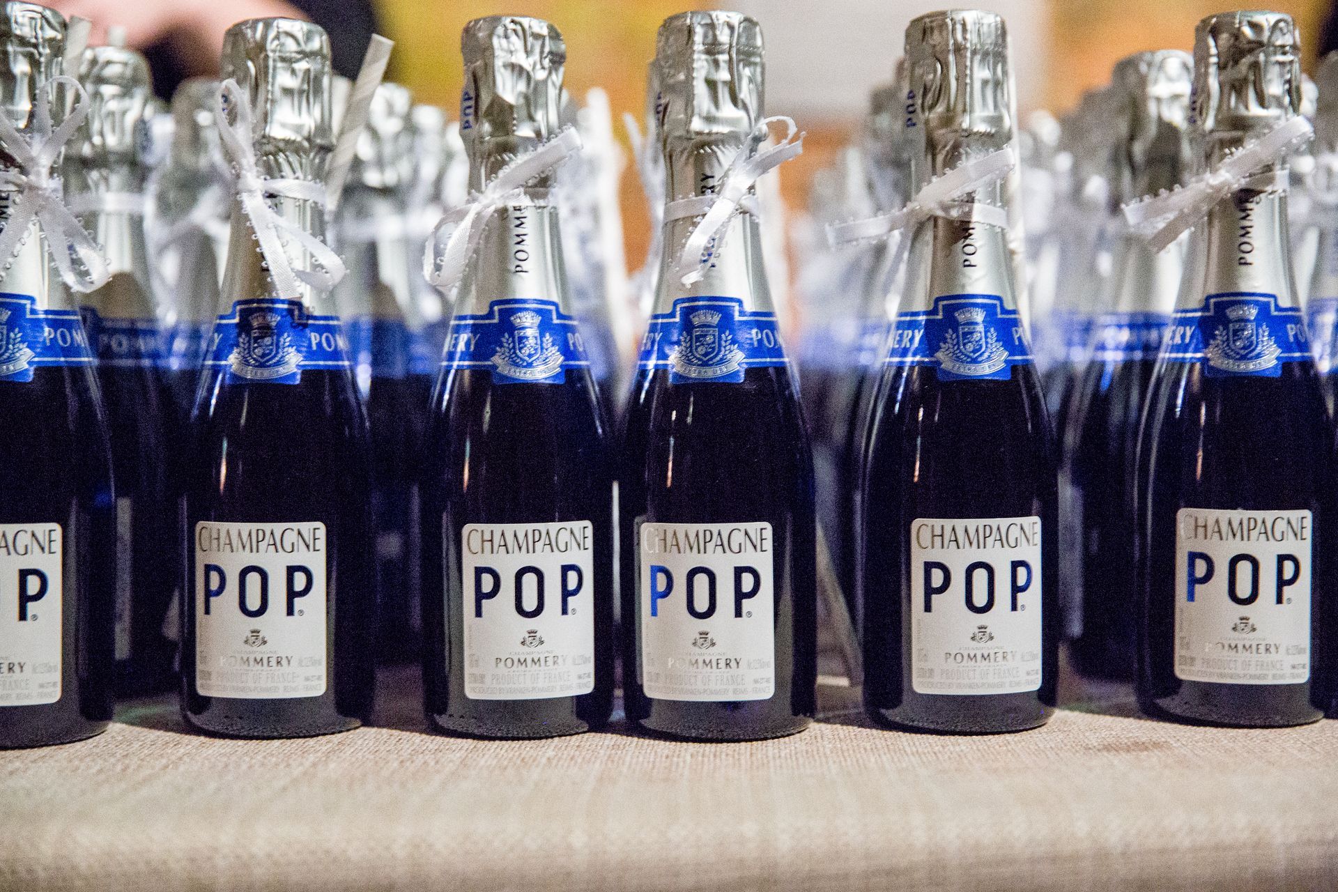 Several bottles of champagne pop are lined up on a table