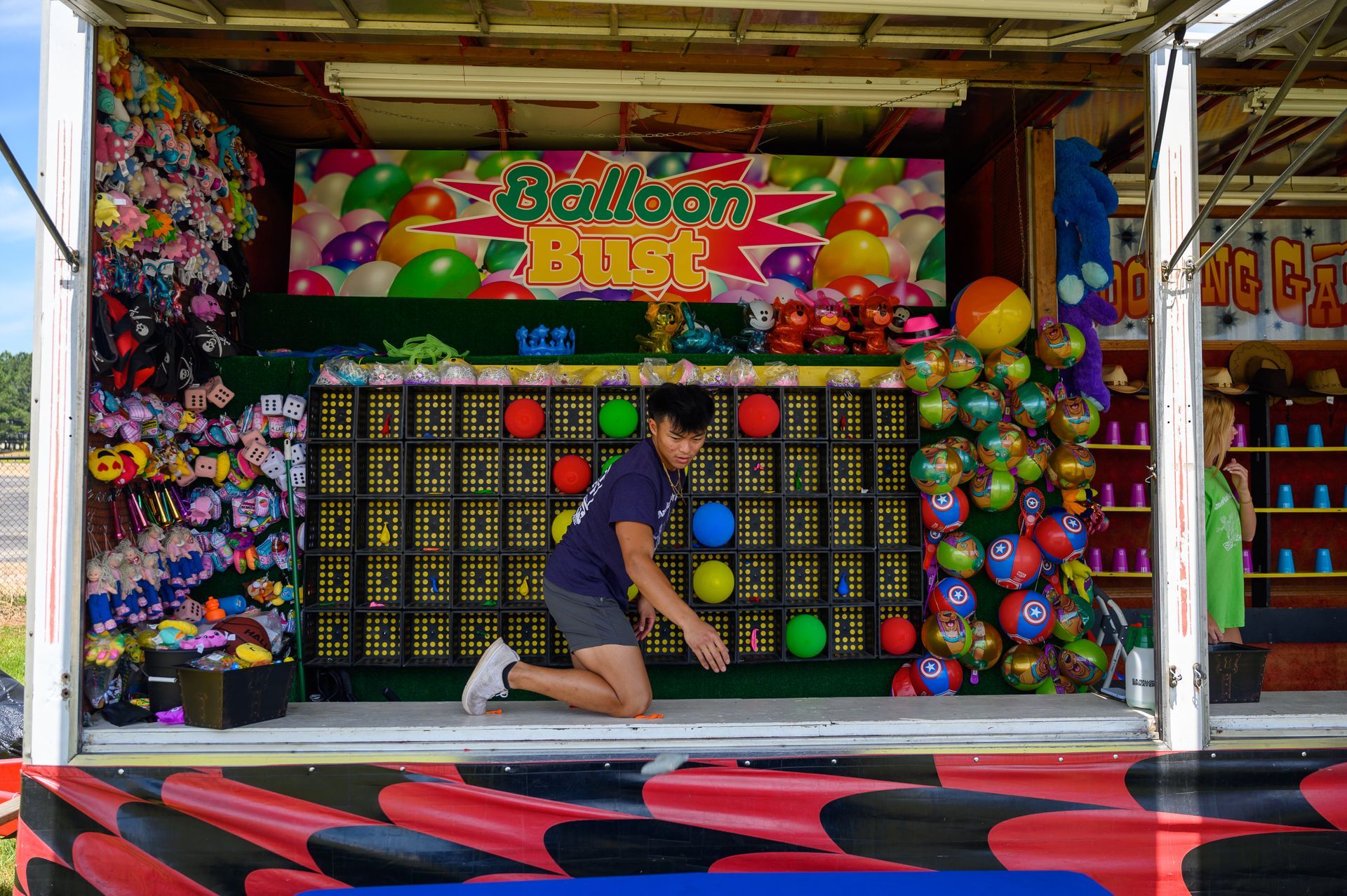 A boy is kneeling in front of a balloon blitz game.