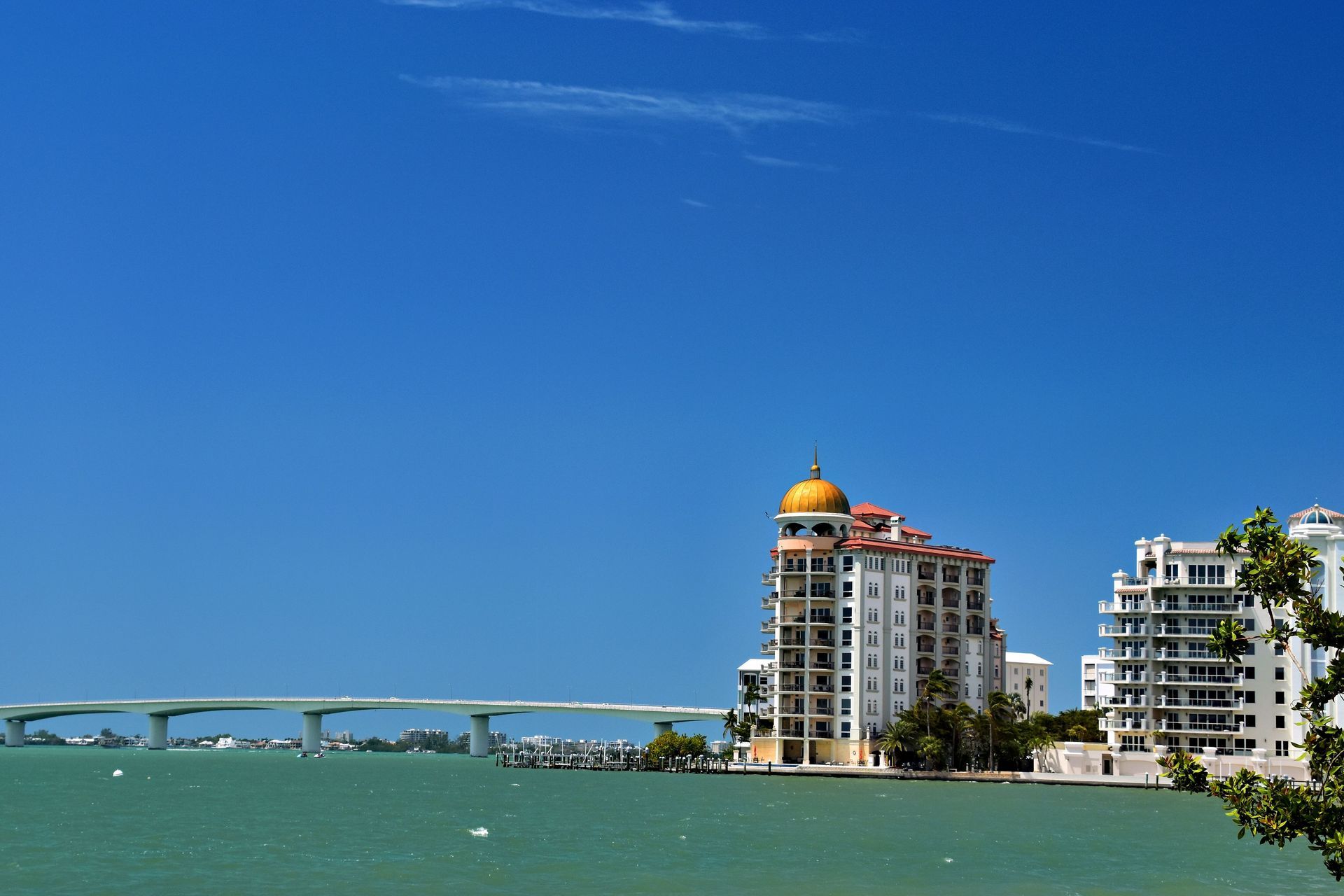 Blue waterfront skyline with a bridge, high-rise buildings, and a clear sky