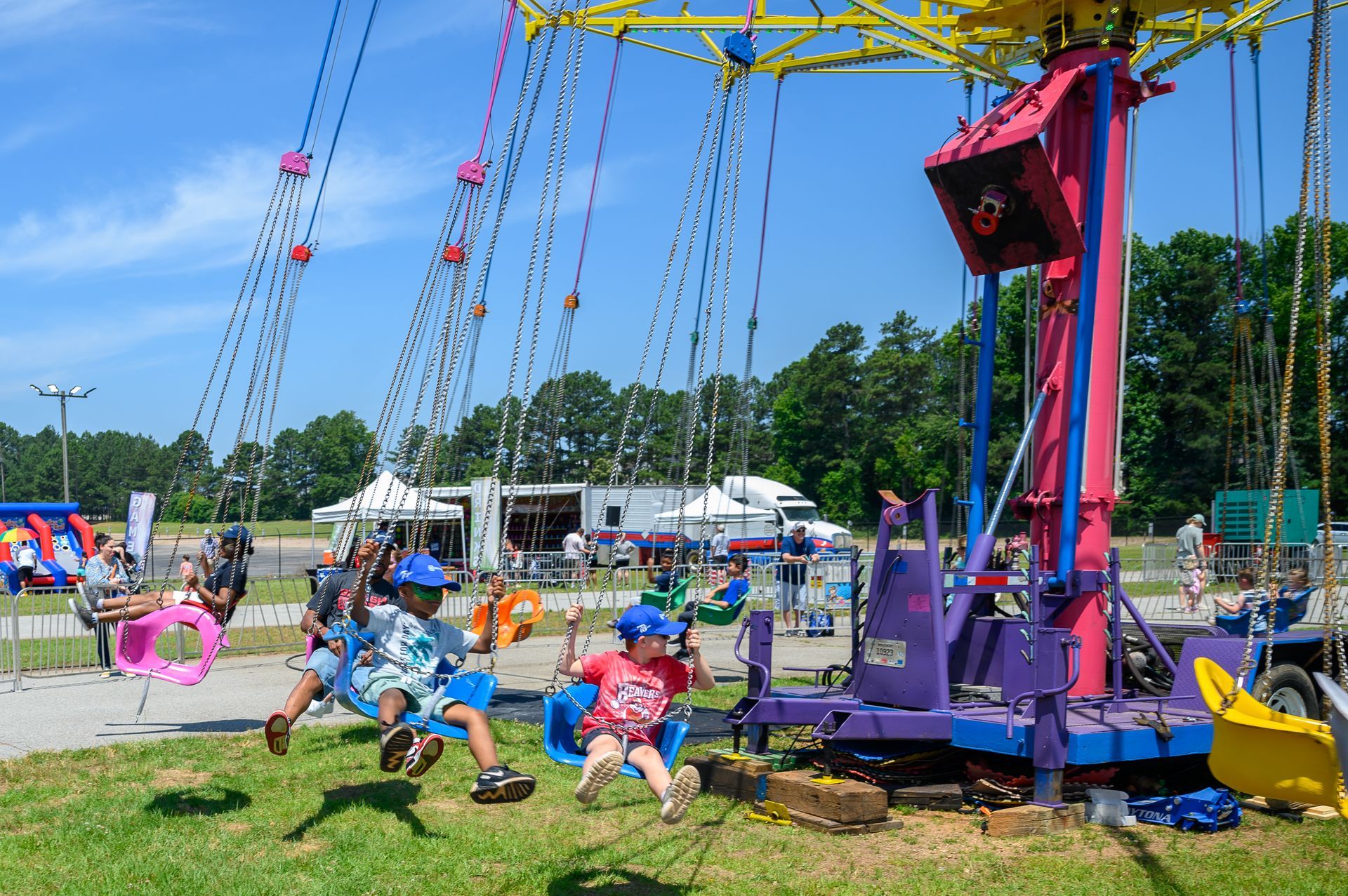 A group of children are riding a swing ride at a carnival.