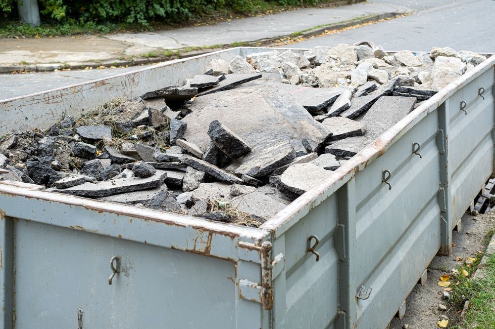 A Dumpster Filled with Rocks and Concrete Is Sitting on The Side of The Road — Hyper Cut & Drill in Swansea, NSW