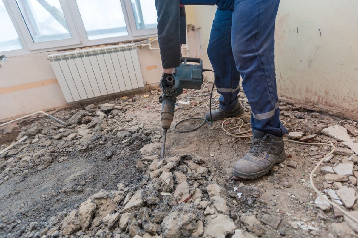 A Man Is Using a Jack Hammer to Drill a Hole in The Floor — Hyper Cut & Drill in Swansea, NSW