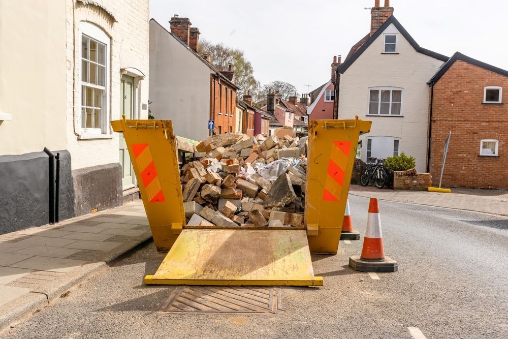 A Yellow Dumpster Filled with Bricks Is Sitting on The Side of The Road — Hyper Cut & Drill in Lake Macquarie, NSW