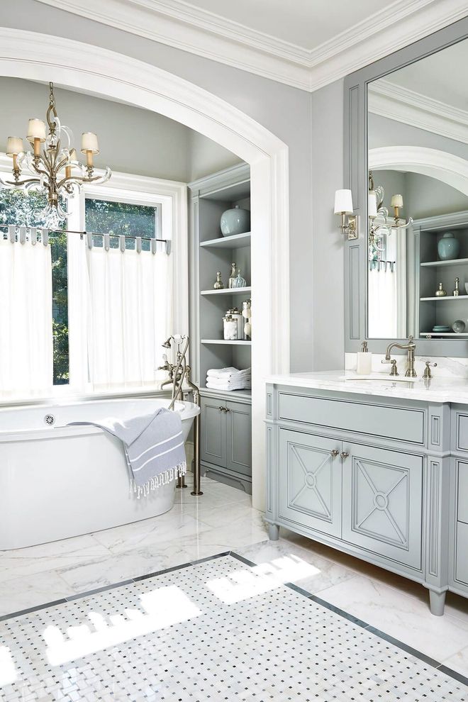 Elegant blue and white bathroom with a soaking tub, vanity, and built-in shelving.