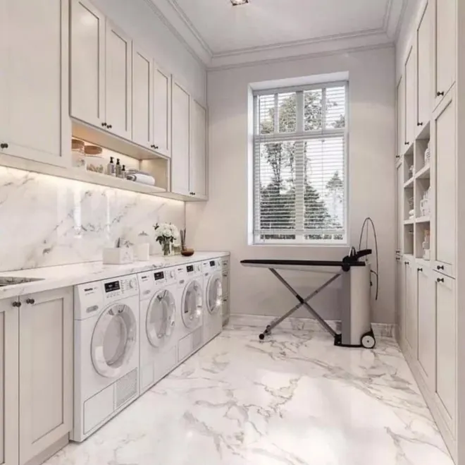 Luxurious laundry room with marble floors, stainless steel appliances, and white cabinets.