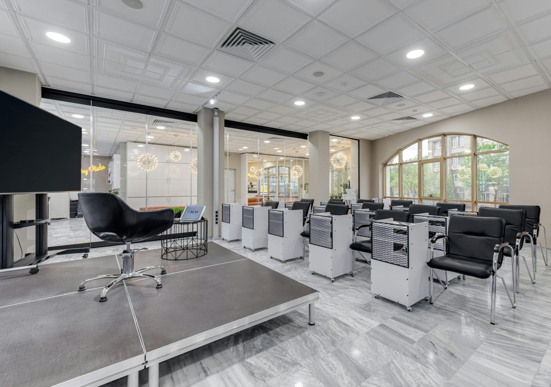 Conference room with a stage, chairs, and AV equipment. White ceiling and marble floors.