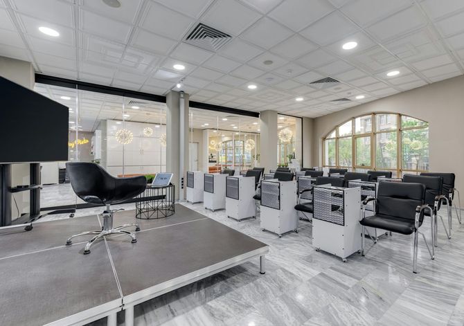 Conference room with a stage, chairs, and AV equipment. White ceiling and marble floors.