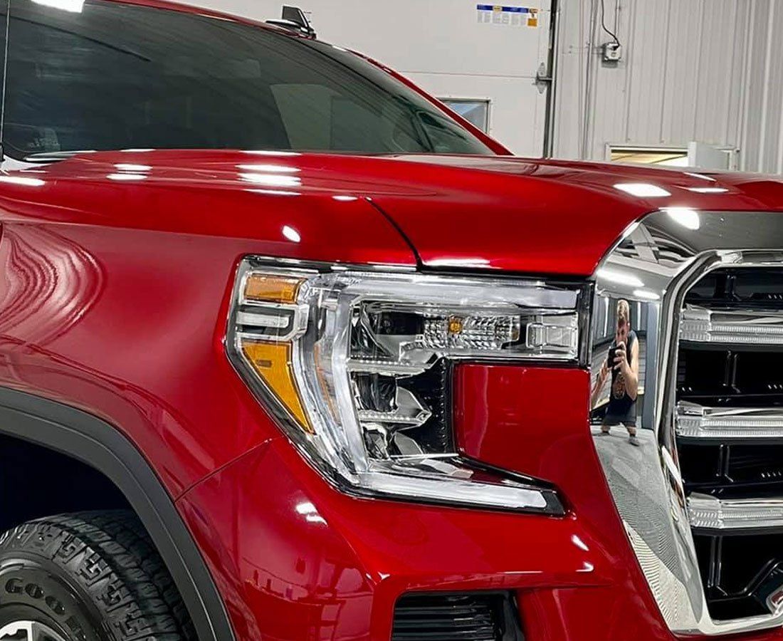 A red truck with a chrome grille is parked in a garage.