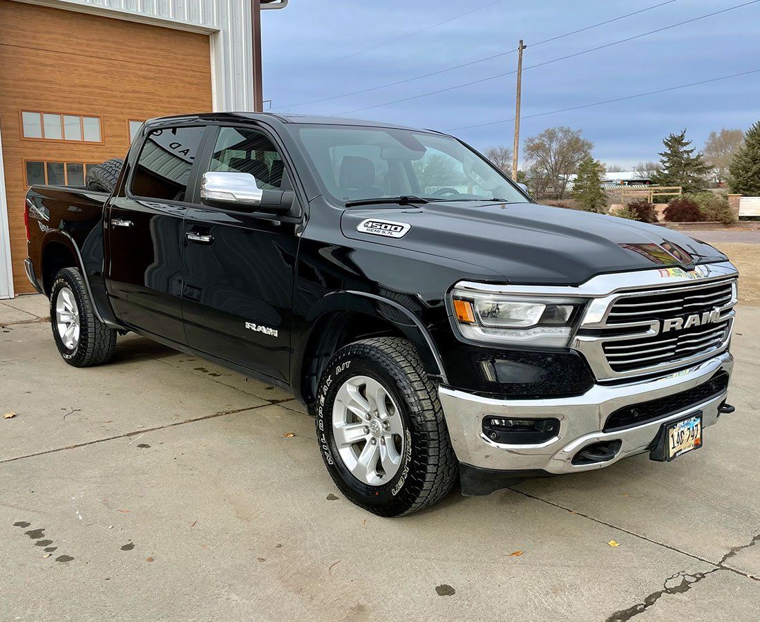 A black ram 1500 truck is parked in front of a garage.