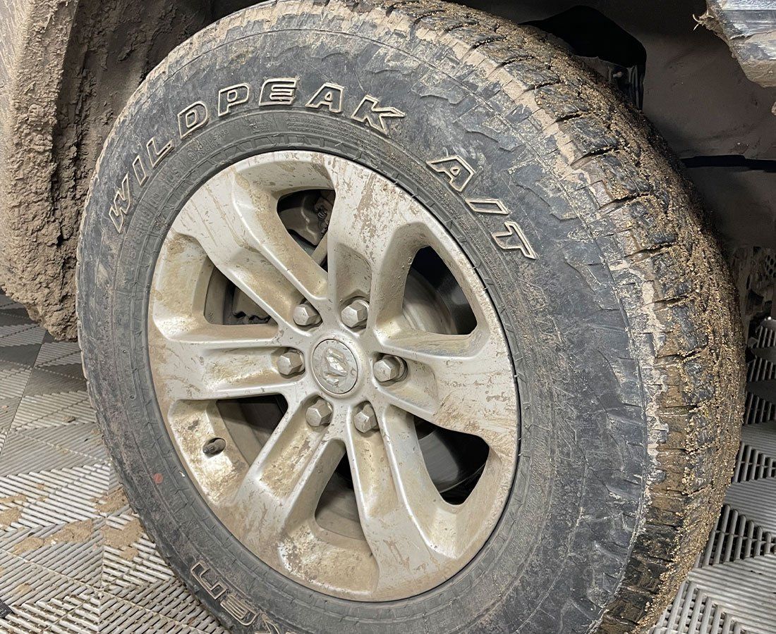 A close up of a muddy tire on a car.