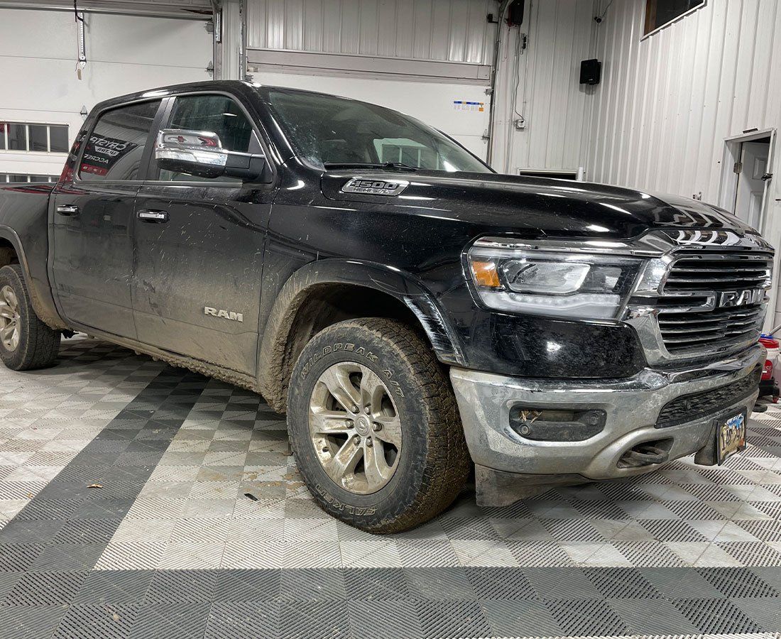 A black ram 1500 truck is parked in a garage.