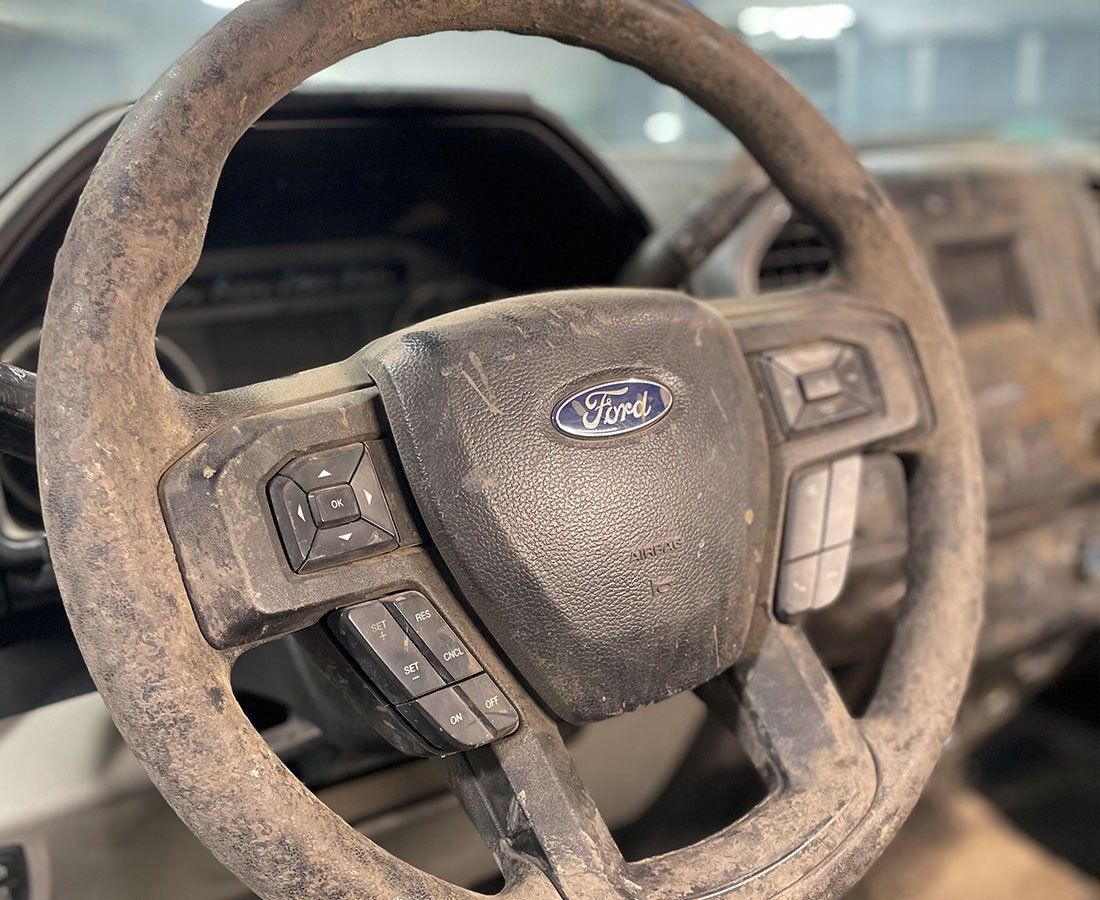 A dirty steering wheel with a ford logo on it
