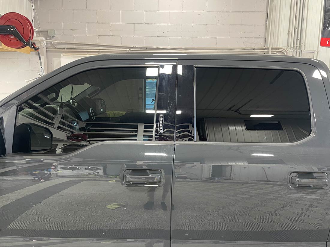 A gray truck is parked in a garage with its doors open.