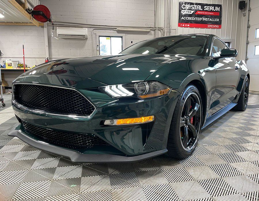 A green ford mustang is parked in a garage.