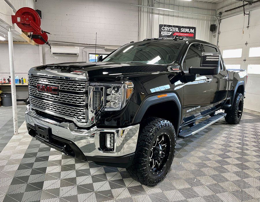A black gmc denali truck is parked in a garage.