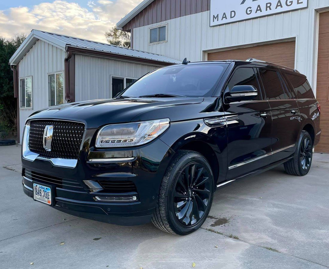 A black ford expedition is parked in front of a garage.