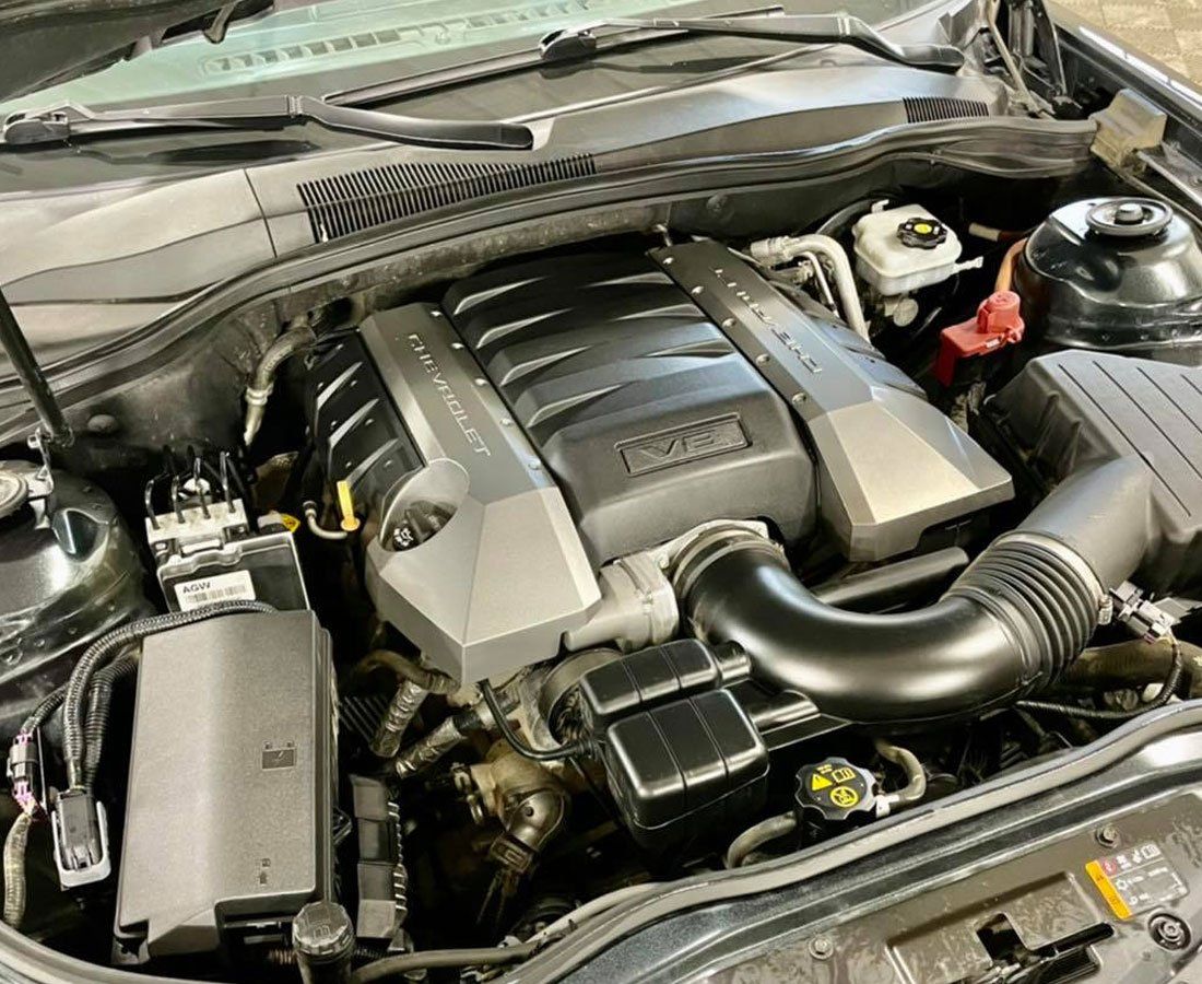 A close up of the engine of a car with the hood open.