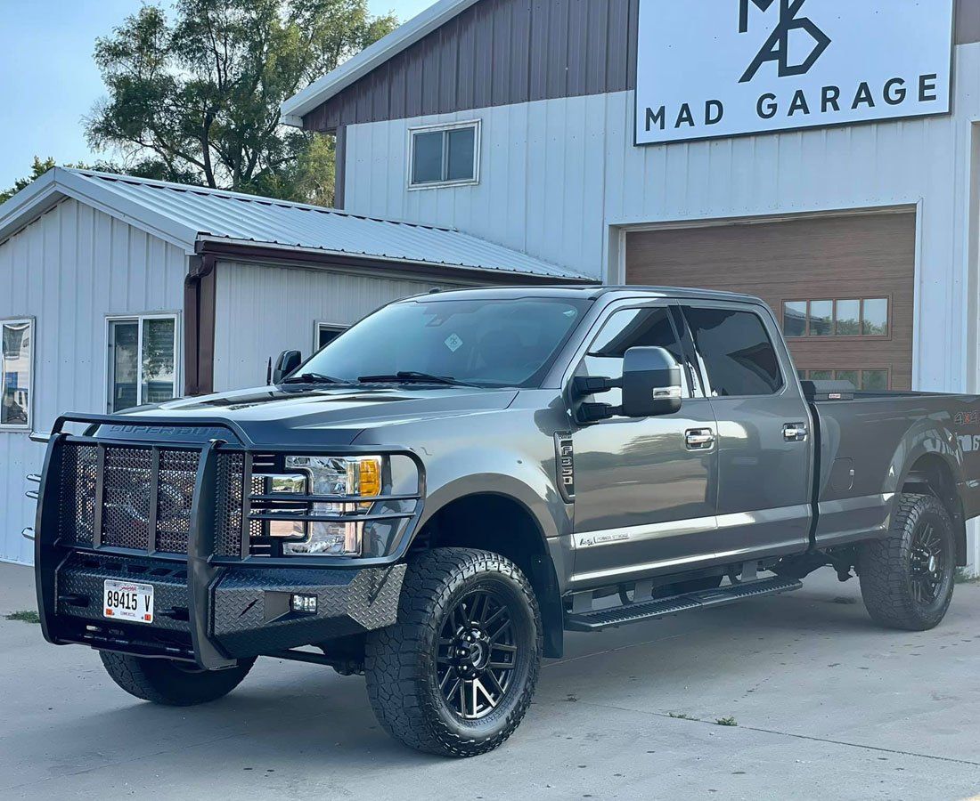 A gray truck is parked in front of a garage.