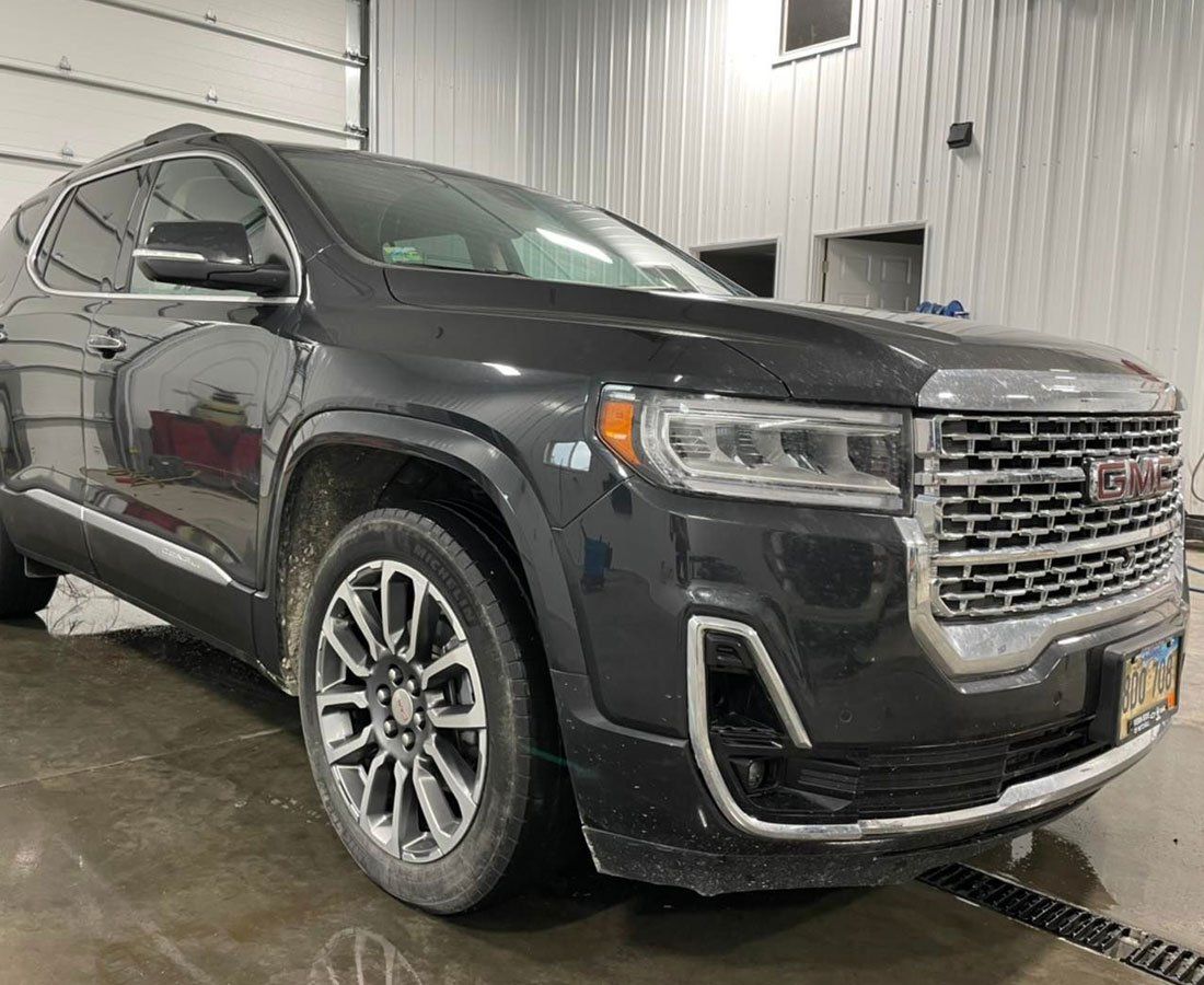 A black gmc acadia is parked in a garage.