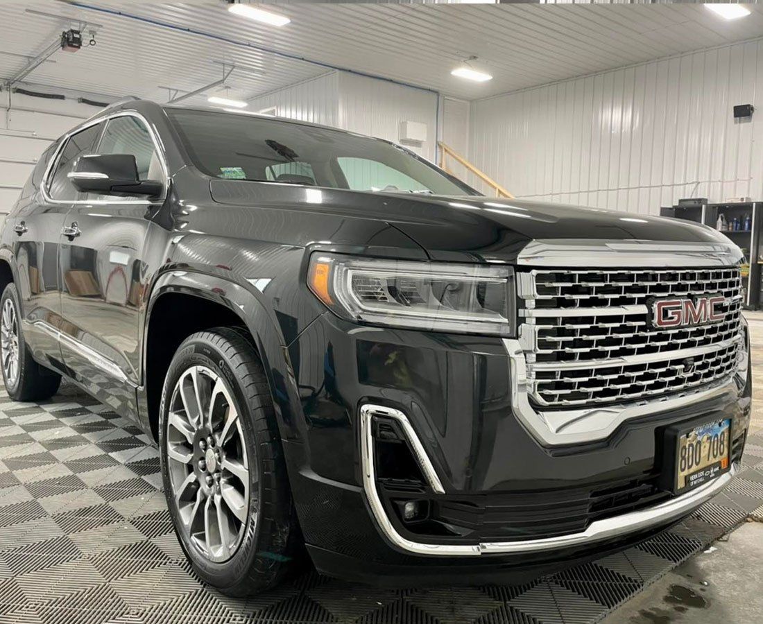 A black gmc acadia is parked in a garage.