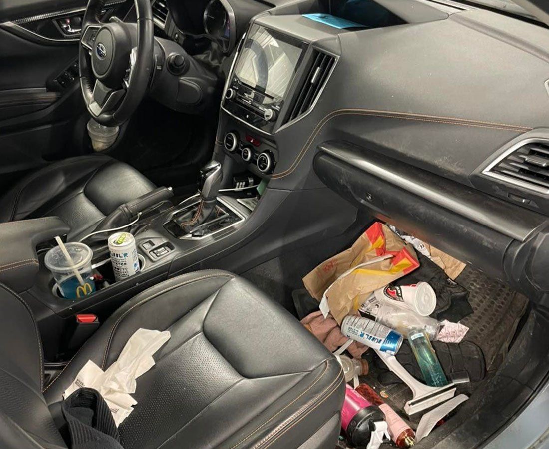 The inside of a car with a lot of trash in it.