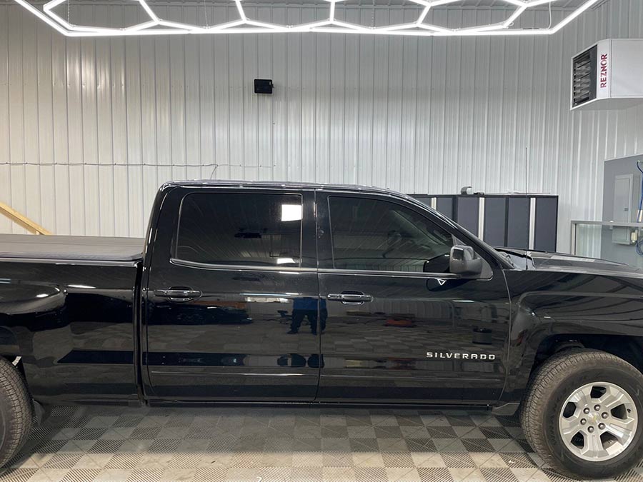 A black pickup truck is parked in a garage.
