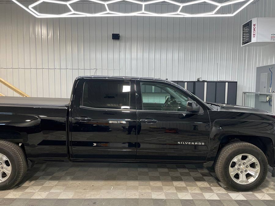 A black pickup truck is parked in a garage.