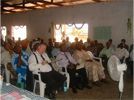 Audience seated indoors at a community gathering, facing a speaker off-camera
