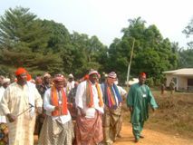 People walking together on a rural dirt road, wearing colorful traditional clothing.