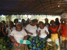 Group of people dancing under a tent, wearing colorful clothes at an outdoor gathering