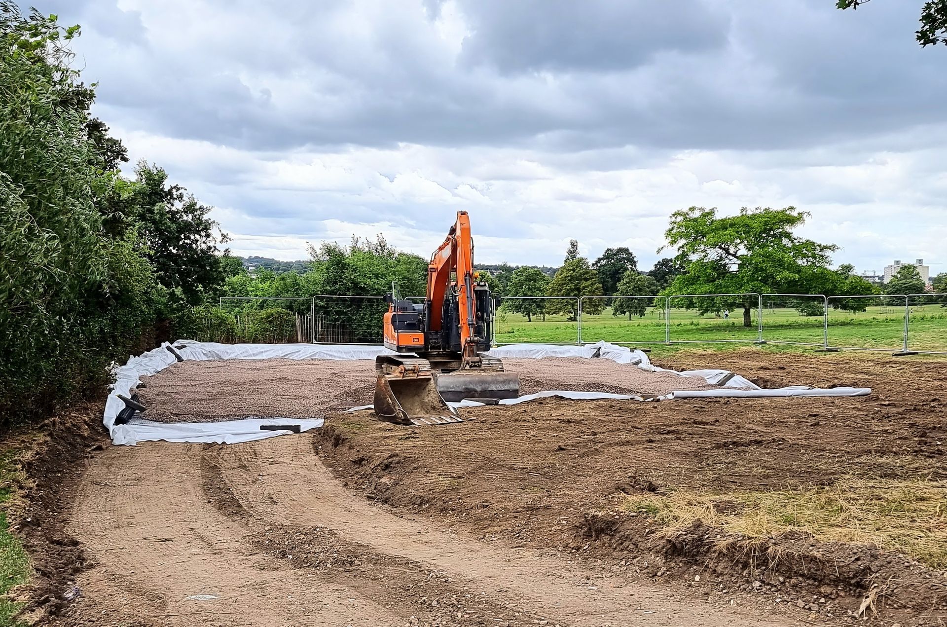 A large orange excavator is sitting in the middle of a dirt field.