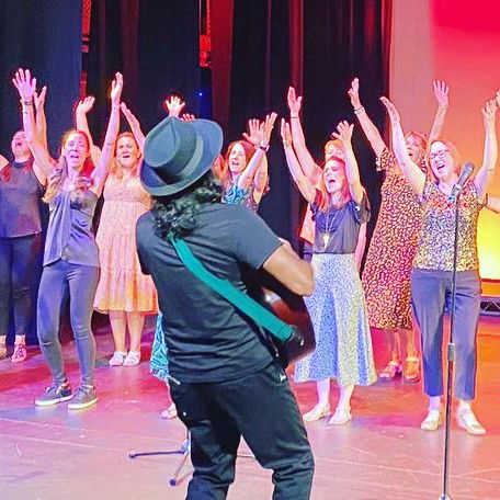 A man is playing a guitar in front of a group of people on a stage.