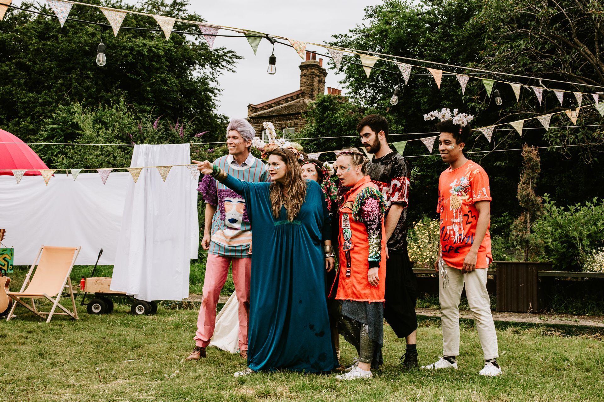Group of people in colorful outfits posing in a garden during an outdoor celebration