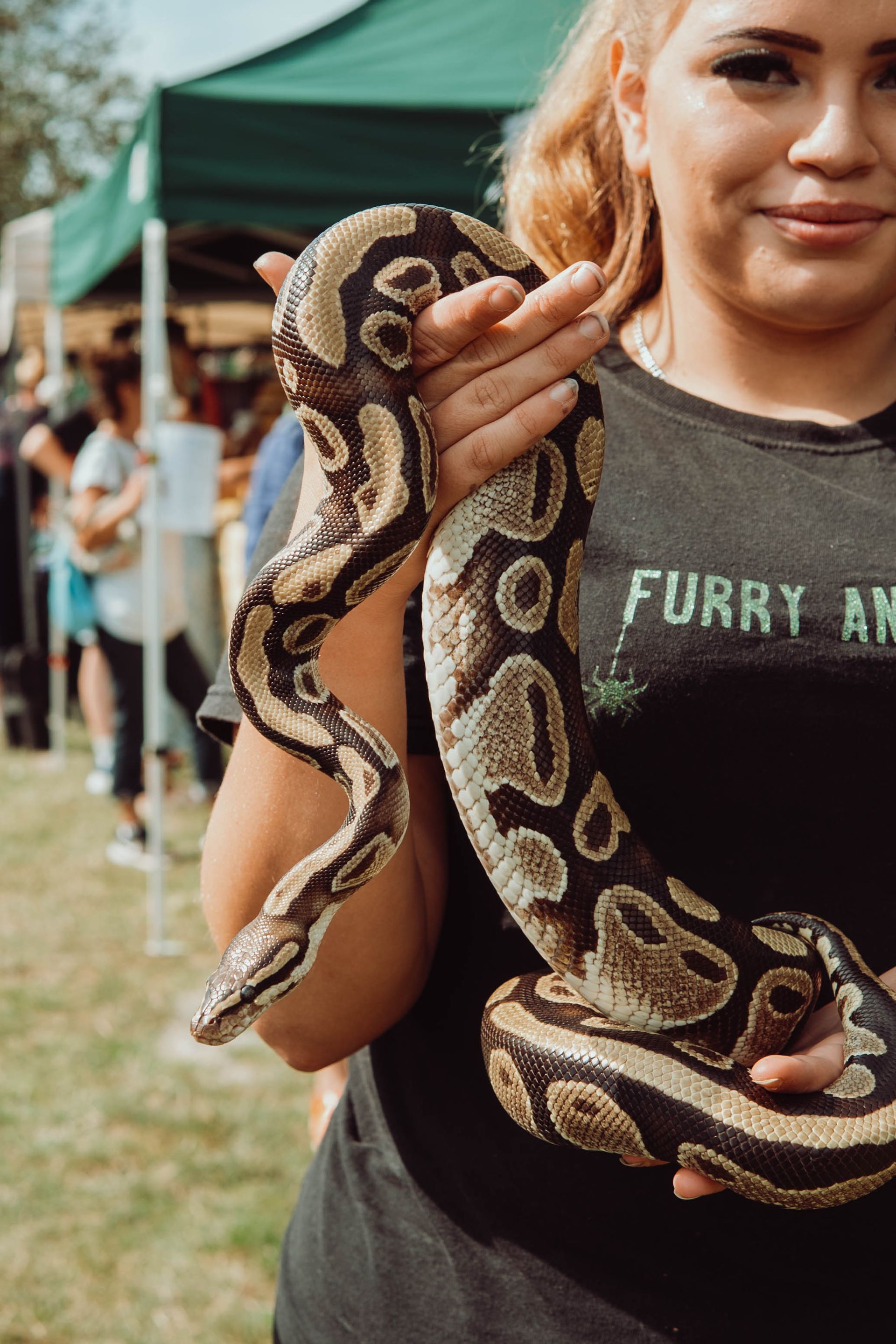 A woman is holding a large snake in her hands.
