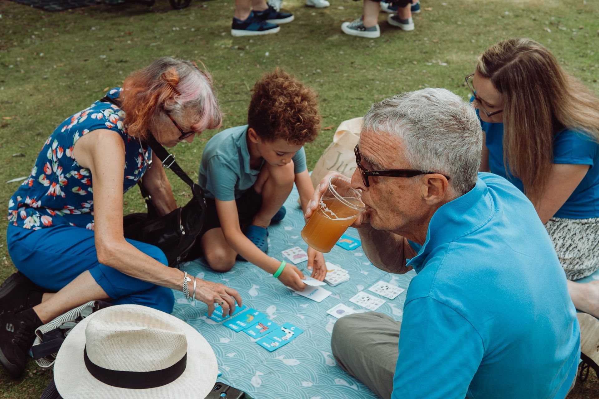 A group of people are sitting on the grass playing a game of cards.