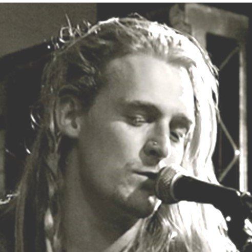 A man with long hair is singing into a microphone