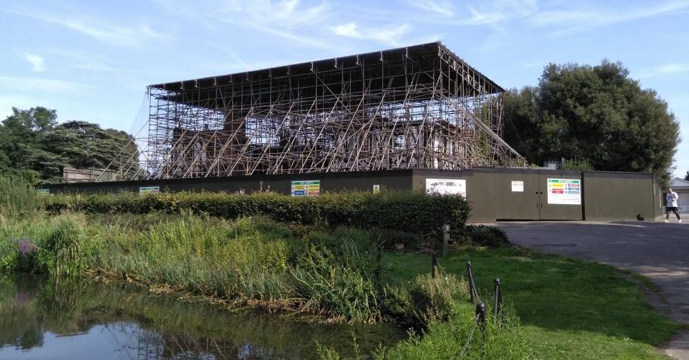 A large building is being built in a park next to a river.