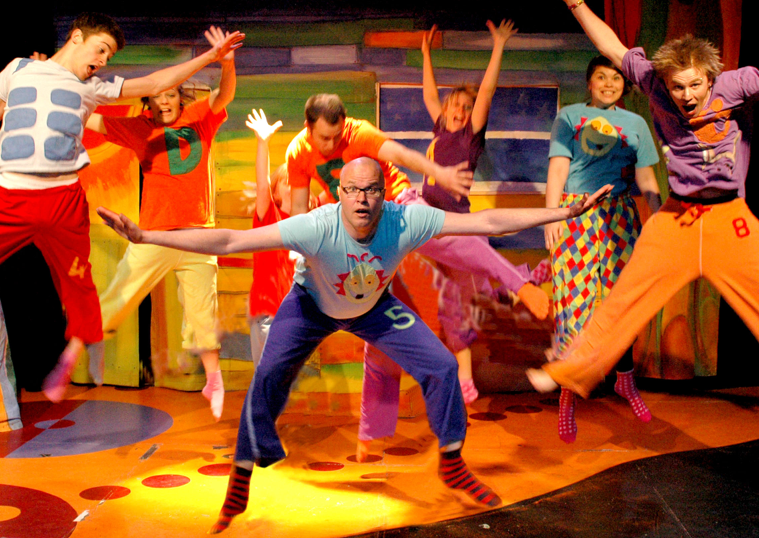 A group of people are jumping in the air on a stage.