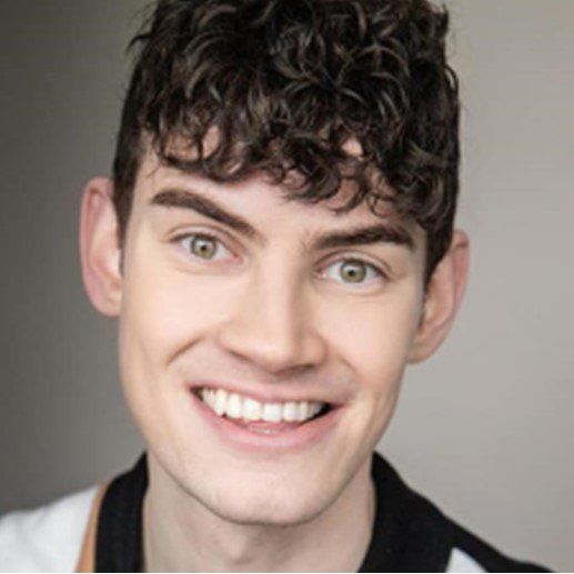 A young man with curly hair is smiling for the camera