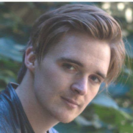 A close up of a young man 's face with trees in the background