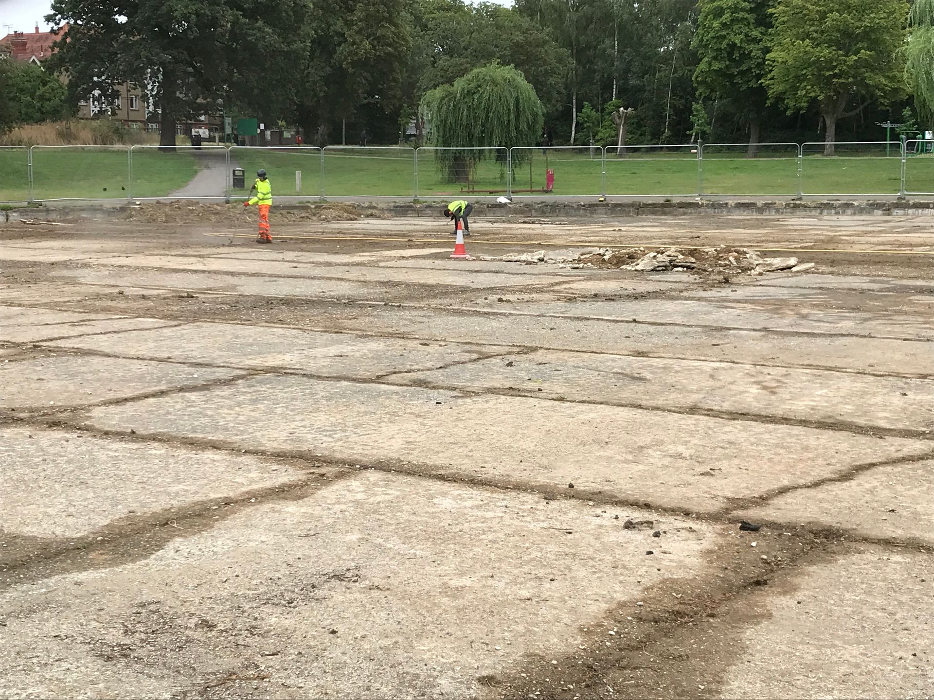 A man in a yellow vest is standing in a drained boating pond