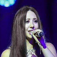 A woman is singing into a microphone on a stage.