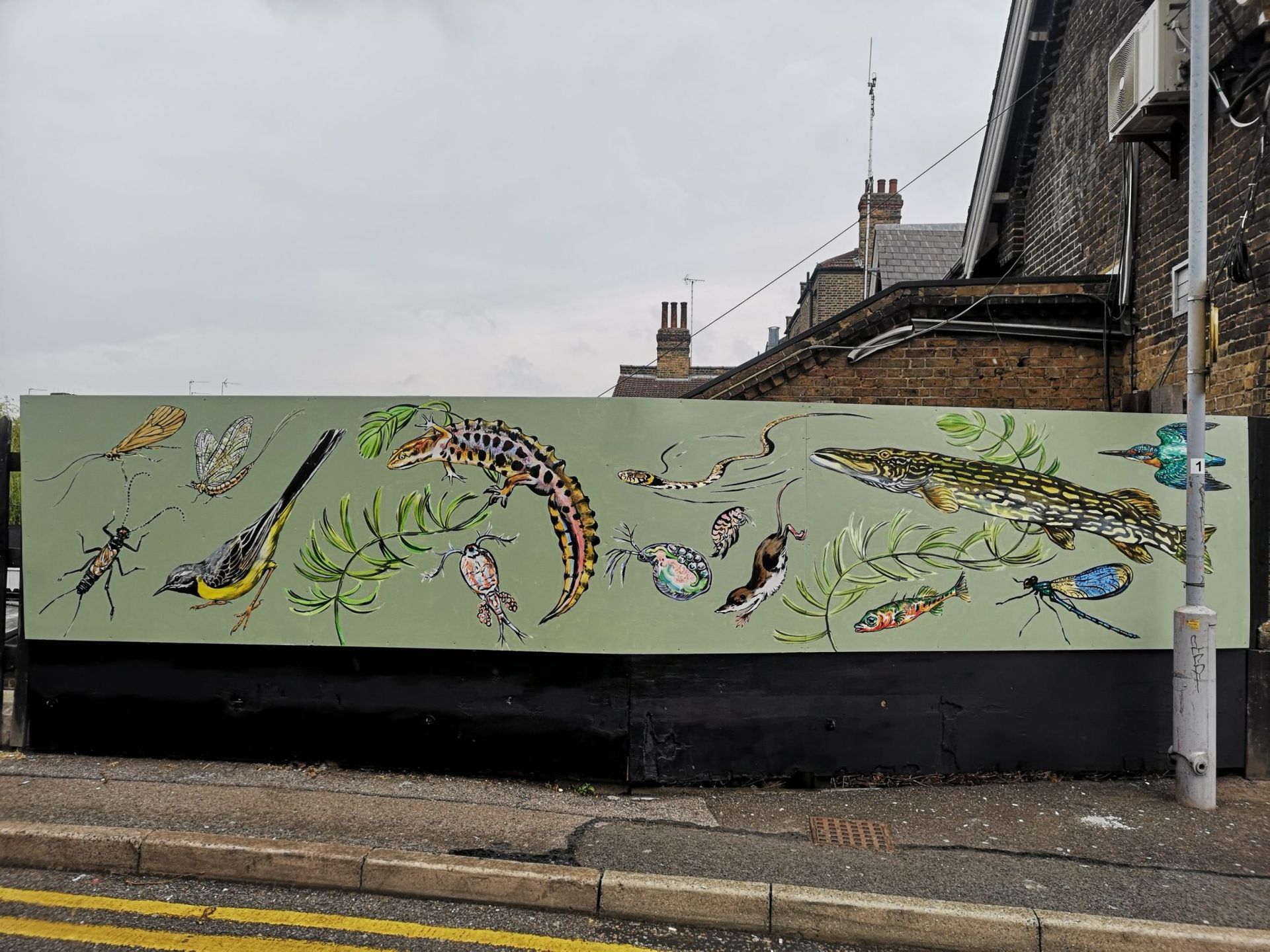 A large billboard with a painting of animals on it is on the side of the road.