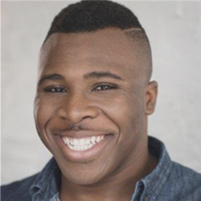 A man with a shaved head is smiling for the camera