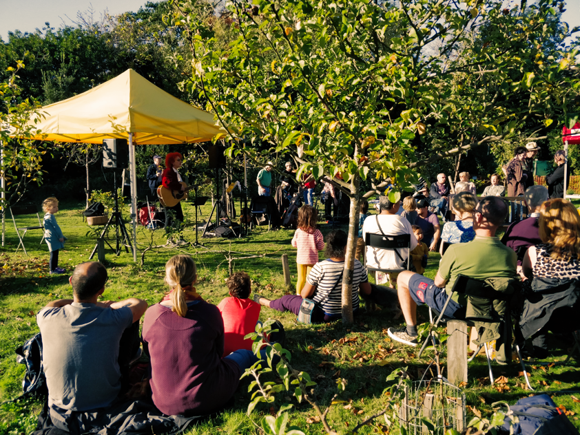 A group of people are sitting in the grass under a yellow tent